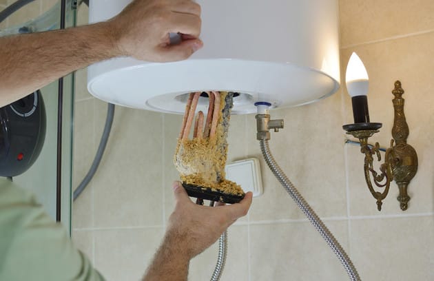 Technician removing mineral buildup from a water heater in Fort Collins