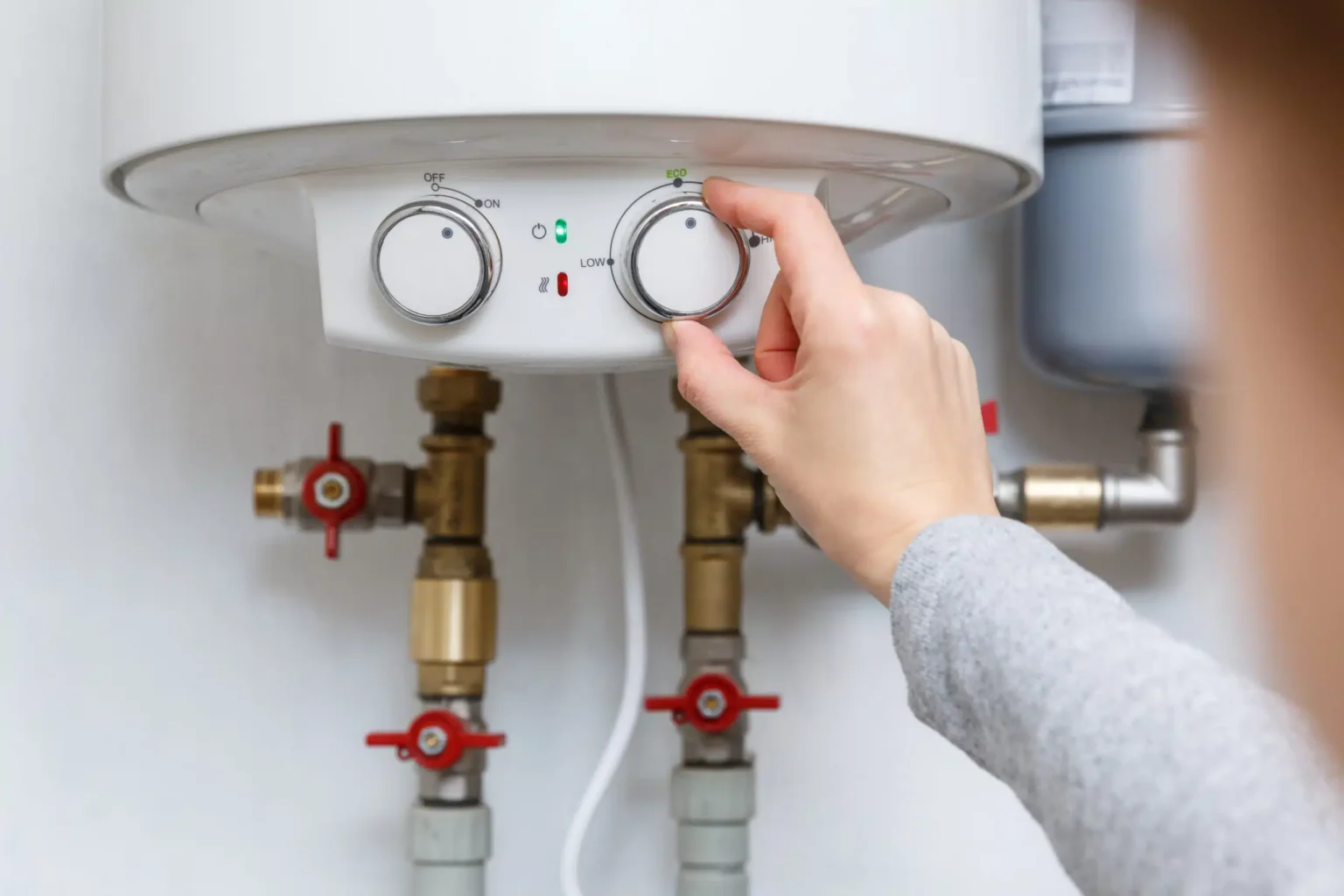 Homeowner adjusting the temperature controls on a water heater in Fort Collins